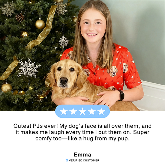 Person wearing a red pajama set with dog prints, holding a dog in front of a decorated Christmas tree.