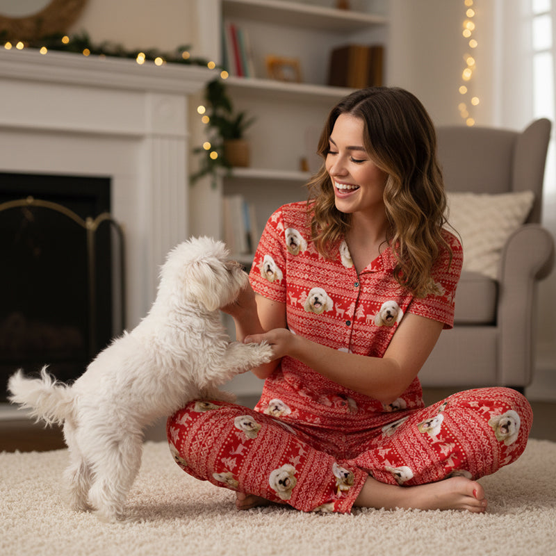 Custom_Pet_Face_Pajama_xm_Fair_Isle_Woman in red pajamas with dog pattern sitting on the floor with a small white dog in a cozy living room.
