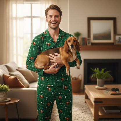 Man wearing green pajamas with dog patterns holding a small brown dog in a living room.