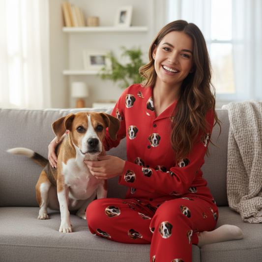 Woman in red pajamas with dog pattern sitting on a couch with a dog.