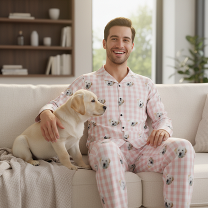 Man in pink pajamas with dog pattern sitting on a couch with a puppy.