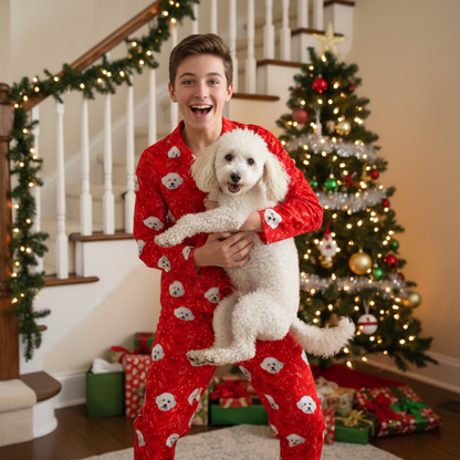 Person in red pajamas holding a white dog with a Christmas tree and decorations in the background