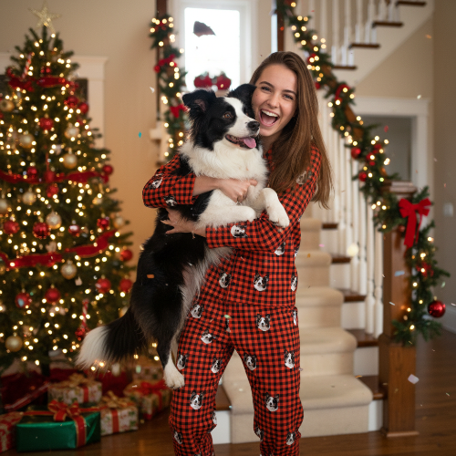 Woman in red plaid pajamas holding a dog in a festive home setting with Christmas trees and decorations.