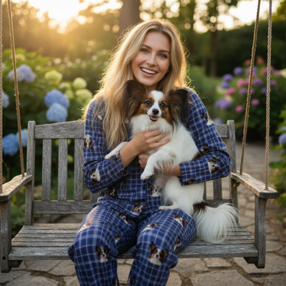 Woman in blue pajamas holding a small dog on a wooden swing with flowers in the background